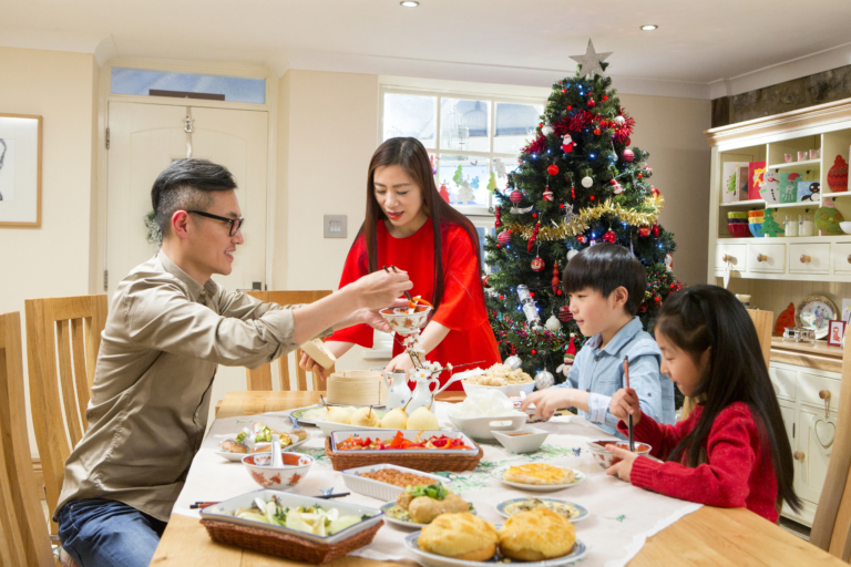 Image of a family of four sharing a meal in front of the Christmas tree